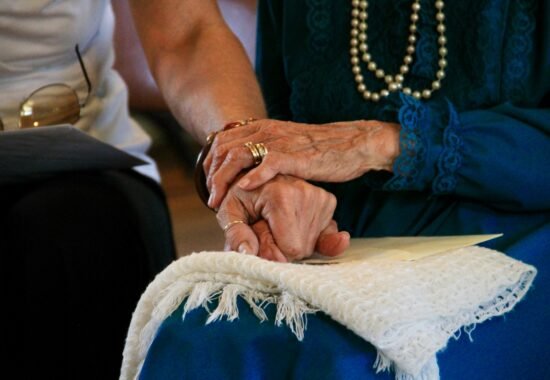 Close up of young person's hand being held by older person